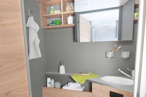 Lichte en moderne toiletruimte met een praktische spiegel die naar opzij kan worden geschoven en veel legplanken en opbergmoge- lijkheden